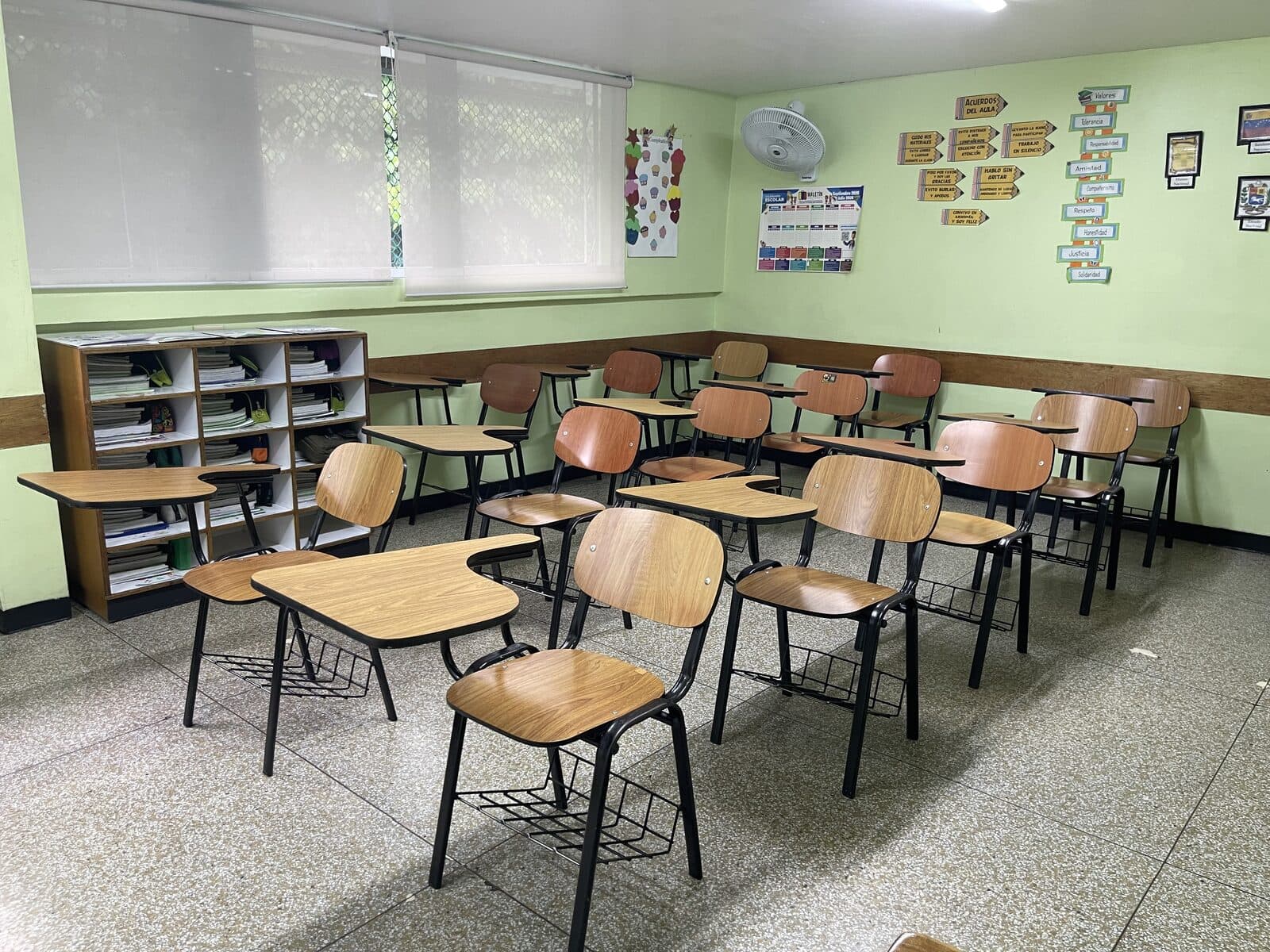Salón de primaria con pupitres y biblioteca de aula