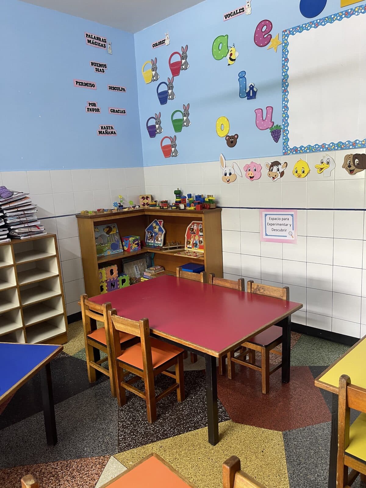 Rincón de lectura de preescolar con mesa roja y libros