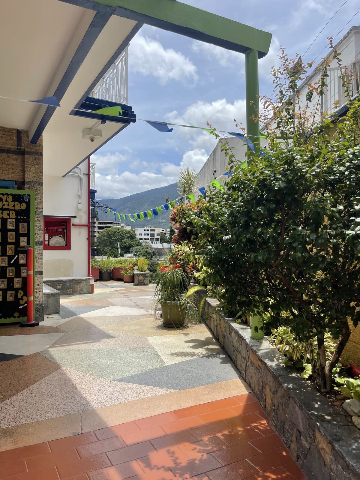 Pasillo cubierto del colegio con jardín y vista a la montaña